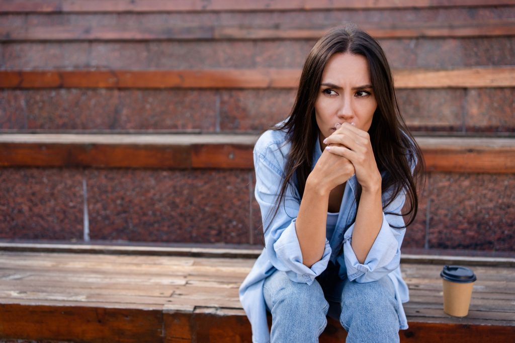 Depressed frustrated woman sitting outdoors feeling stressed, worried, mental problems concept