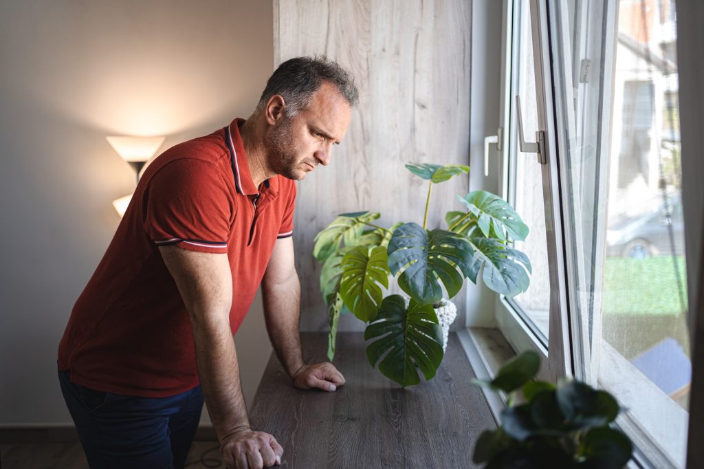 Man standing by the window looking sad and distraught